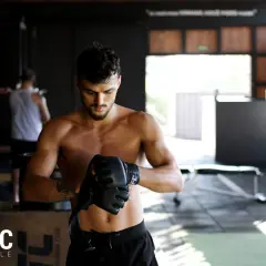 Mężczyzna w rękawicach MMA w siłowni.