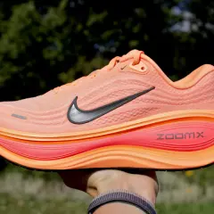 Pomarańczowy but do biegania Nike z czarnym logo i podeszwą ZoomX.