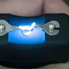 Paralizator z iskrzącymi elektrodami w dłoni.
