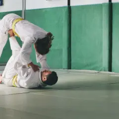 Dwie osoby w judogach ćwiczą rzuty. Judo to jeden ze sportów walki na olimpiadzie.