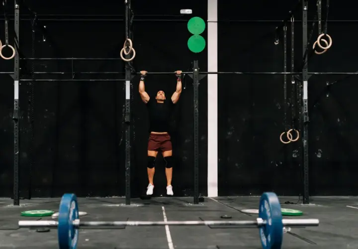 Mężczyzna wykonujący podciąganie na drążku w siłowni CrossFit.