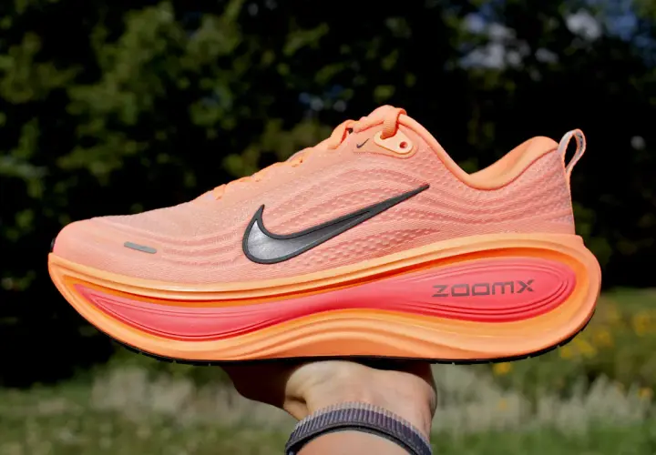 Pomarańczowy but do biegania Nike z czarnym logo i podeszwą ZoomX.