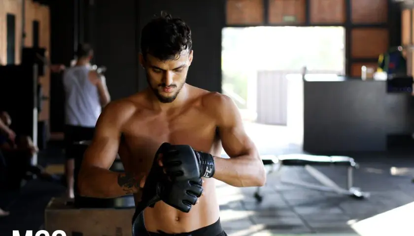 Mężczyzna w rękawicach MMA w siłowni.
