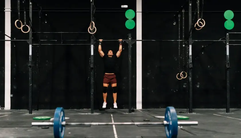 Mężczyzna wykonujący podciąganie na drążku w siłowni CrossFit.