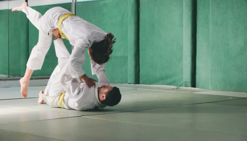 Dwie osoby w judogach ćwiczą rzuty. Judo to jeden ze sportów walki na olimpiadzie.