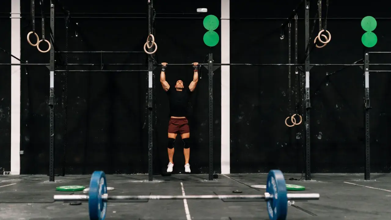 Mężczyzna wykonujący podciąganie na drążku w siłowni CrossFit.