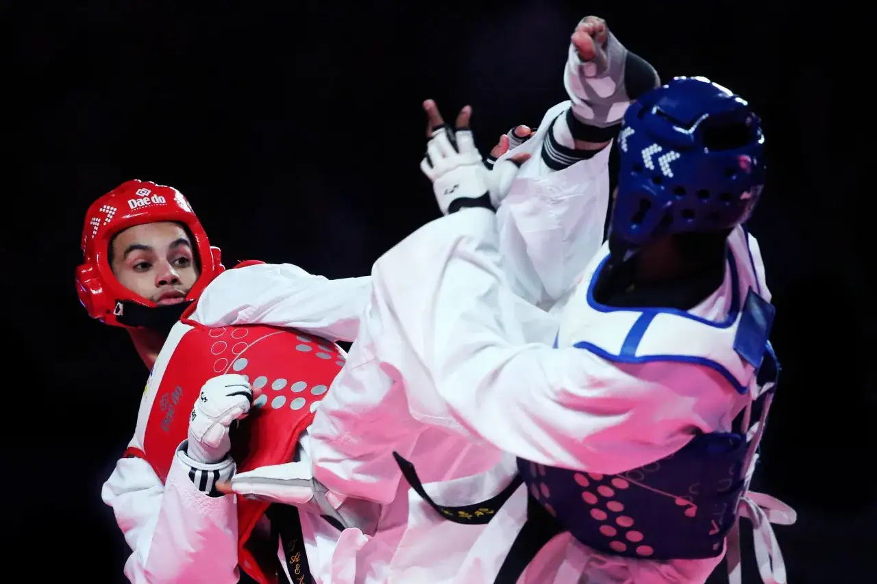 Dwaj zawodnicy taekwondo w akcji. Ta dyscyplina to jeden ze sportów walki na Olimpiadzie, pełen dynamicznych kopnięć i bloków.